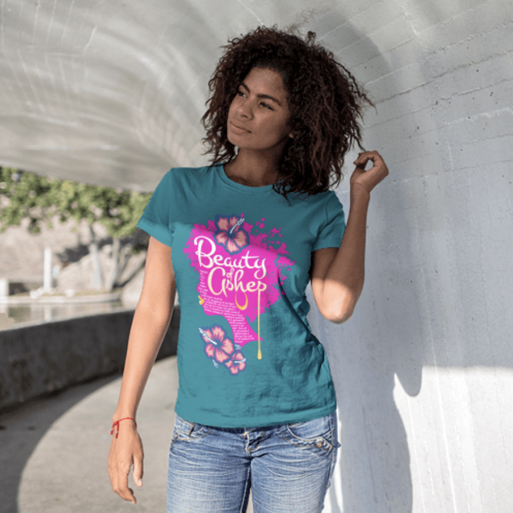 Teal t-shirt mockup of Beauty of Ashes scripture art, worn by a woman leaning against a concrete wall in natural light